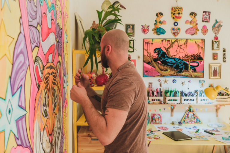 Artist man with beard and bald head looking away as he works on a bright pop artwork