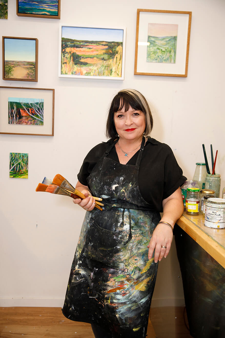 artist iwith painting apron n front of studio wall