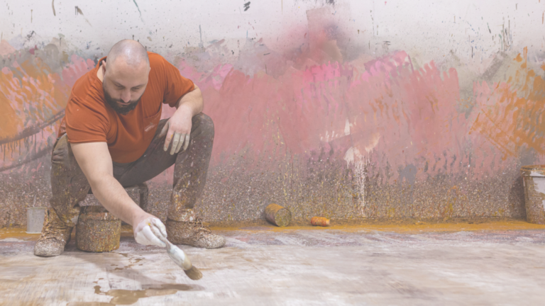 man squatting and painting on floor